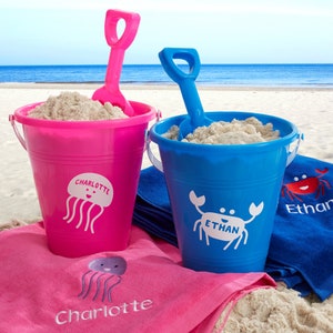 May include: Two personalized beach pails with shovels, one pink with a jellyfish design and the name Charlotte, and one blue with a crab design and the name Ethan.