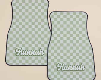 May include: Two green and white checkered car floor mats with black edging. The mats have the name "Hannah" written in a retro font.