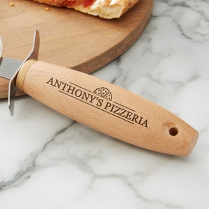 Peut inclure: Un coupe-pizza en bois avec une lame en acier inoxydable. Le manche est grav&eacute; avec "Anthony's Pizzeria" et une petite ic&ocirc;ne de part de pizza.