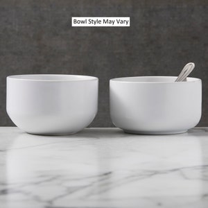 May include: Two white ceramic bowls, one with a spoon inside, on a white marble surface. The text "Bowl Style May Vary" is displayed above the bowls.