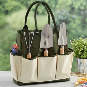 Peut inclure: Un sac de jardinage en toile vert avec plusieurs poches et un ensemble d'outils de jardinage, y compris une pelle, un r&acirc;teau &agrave; main et un d&eacute;sherbeur. Le sac est doubl&eacute; de cr&egrave;me.