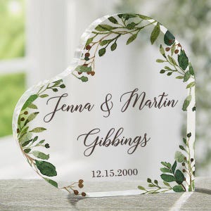 May include: A clear heart-shaped glass keepsake with a leafy green and brown floral design. The text "Jenna & Martin Gibbing 12.15.2000" is printed on the glass.