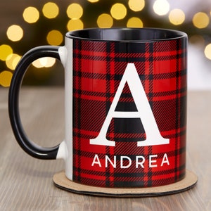 Puede incluir: Una taza negra y blanca con un patr&oacute;n de cuadros rojos y negros. La taza tiene una letra blanca "A" y el nombre "ANDREA" impreso en ella.