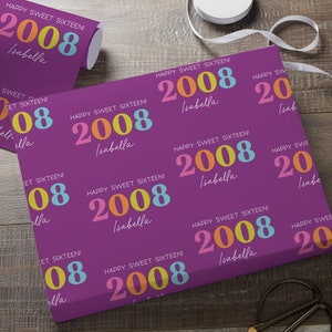 May include: Purple wrapping paper with a repeating pattern of the text "HAPPY SWEET SIXTEEN!" and the year "2008" in colorful text. The name "Isabella" is also printed on the paper.