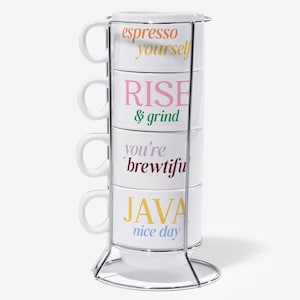 May include: A stackable white ceramic coffee cup set with a metal stand. Each cup has a different colorful phrase: "espresso yourself", "RISE & grind", "you're brewtiful", and "JAVA nice day".