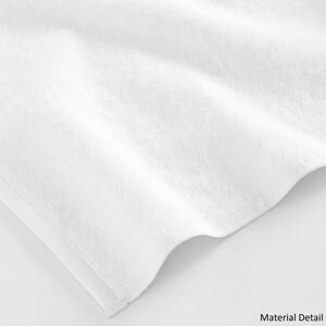 May include: Close-up of a white, soft, and fluffy towel. The towel is made of a plush material and has a smooth texture.