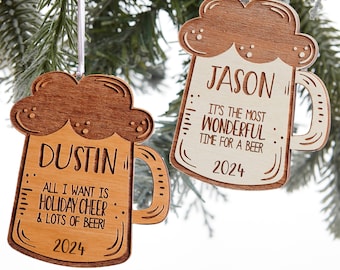 May include: Two wooden beer mug Christmas ornaments. One says "DUSTIN" and "ALL I WANT IS HOLIDAY CHEER & LOTS OF BEER!" with "2024". The other says "JASON" and "IT'S THE MOST WONDERFUL TIME FOR A BEER" with "2024". Both have a light wood color.