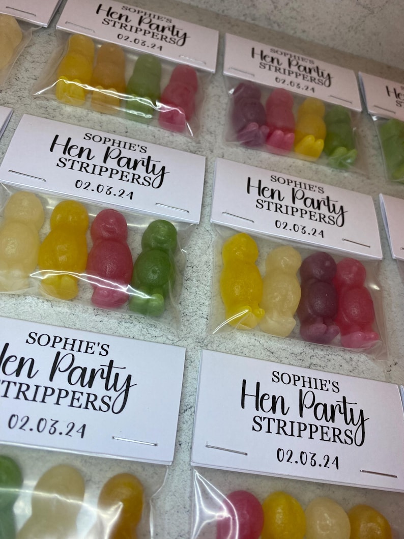 May include: A set of small clear plastic bags with colorful candy and a white card with black text that reads "Sophie's Hen Party Strippers 02.03.24".