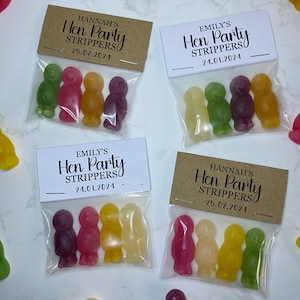 May include: Four small bags filled with colorful candy, each bag has a personalized tag with the text "Hen Party Strippers" and a date.
