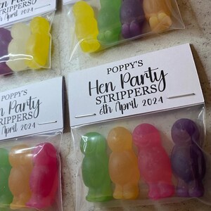 May include: Four small bags with clear cellophane fronts and white card backs. Each bag contains four gummy candies shaped like people. The cards have the text "Poppy's Hen Party Strippers 6th April 2024".