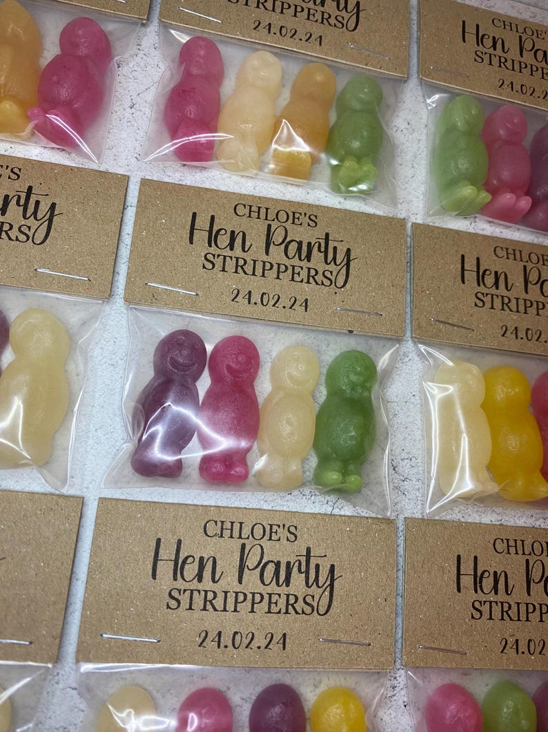 May include: A set of small, clear plastic bags filled with colorful candy. Each bag has a brown card attached with the text "CHLOE'S Hen Party Strippers" and a date.