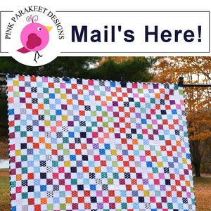 May include: A colorful quilt with a checkerboard pattern made using the quick strip piecing method. The quilt is hanging on a clothesline outdoors. The quilt is made with a variety of fabrics, including white, black, red, blue, green, yellow, and purple. The quilt is titled "Mail's Here!" and is made by Pink Parakeet Designs.