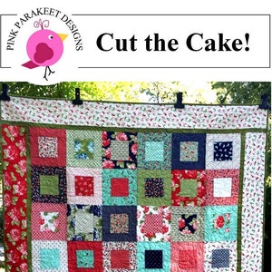 Könnte beinhalten: Eine Quiltdecke mit einem Layer-Cake-Design, das eine Vielzahl von Blumenstoffen in Rot-, Grün-, Blau- und Weißtönen zeigt. Die Quiltdecke hängt an einer Wäscheleine im Freien. Die Quiltdecke ist mit "Cut the Cake!" und "Layer Cake Friendly" beschriftet.