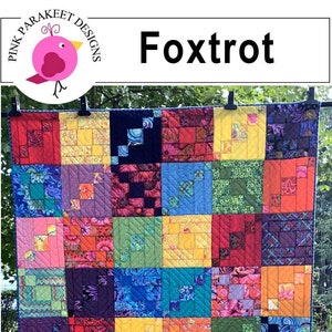 Könnte beinhalten: Ein farbenfroher Quilt mit Patchwork-Muster, der eine Vielzahl von Stoffen in Rot-, Blau-, Grün-, Gelb- und Lilatönen zeigt. Der Quilt ist mit "Fox Trot" und "Fat Quarter Friendly" beschriftet.