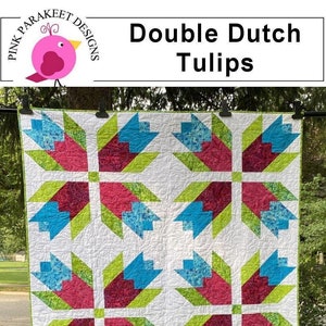 May include: A quilt block with a "Double Dutch Tulips" design. The block is made up of 9 squares, each with a different pattern of blue, green, pink, and white fabric. The block is 26 inches wide.