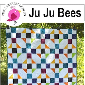 May include: A colorful quilt with a geometric pattern of squares and triangles in shades of blue, green, yellow, orange, red, and black. The quilt is hanging on a clothesline outdoors. The text "Ju Ju Bees" and "Quick Strip Piecing!" is visible on the quilt.