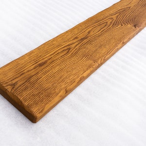 May include: A long, rectangular piece of wood with a natural, brown finish. The wood has a grain pattern and is smooth to the touch.