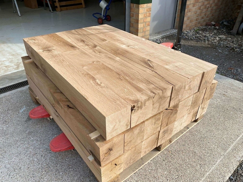 May include: A stack of rough-cut, light brown wooden planks, likely oak, on a pallet. The planks are stacked neatly and have a natural, rustic appearance.