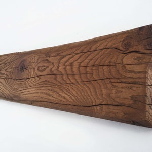 May include: A long, rustic wooden beam with a natural brown finish. The wood has a knot and a grain pattern. The beam is slightly curved.