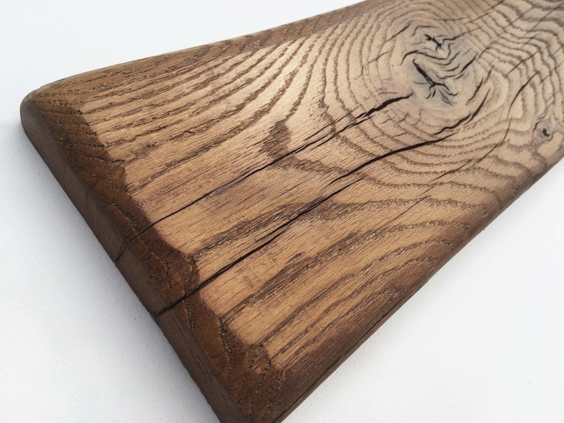 May include: A close-up of a rustic wooden plank with a natural brown finish. The wood has a knot and a crack running through it, showcasing its unique character.
