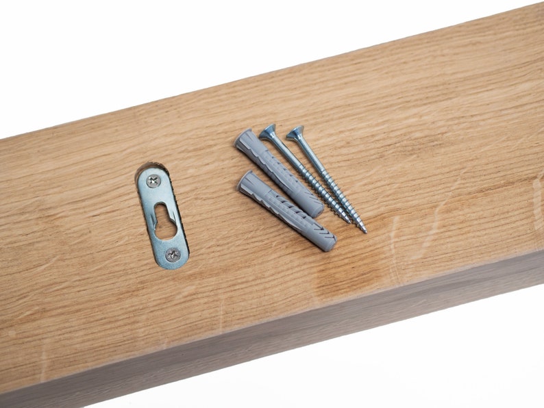 May include: A wooden shelf with a metal hanging bracket and three screws and plastic anchors. The shelf is light brown and the screws are silver.