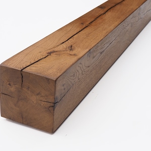 May include: A large, rustic, brown wooden beam with a natural finish. The beam has a large crack running down the center. The beam is made of reclaimed wood and has a unique character.