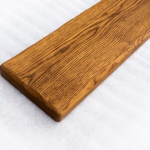 May include: A long, rectangular piece of wood with a natural, brown finish. The wood has a grain pattern and is smooth to the touch.