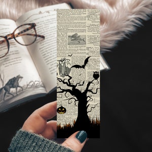 May include: A Halloween-themed bookmark featuring a black silhouette of a tree with branches, a bat, an owl, and a jack-o'-lantern on a vintage dictionary page background.