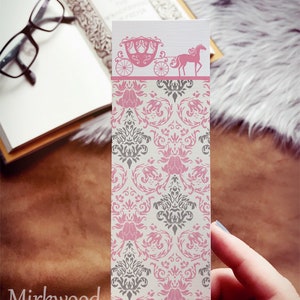 Könnte beinhalten: Ein rosa und graues Lesezeichen mit einem Damastmuster. Die Oberseite des Lesezeichens zeigt eine rosa Silhouette einer von einem Pferd gezogenen Kutsche.