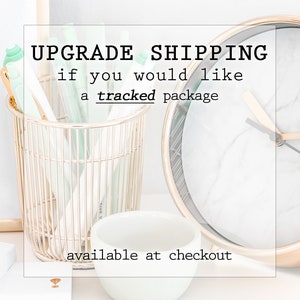 May include: A gold wire basket filled with green and white pens, a white ceramic bowl, and a gold clock with a white marble face. The text "UPGRADE SHIPPING if you would like a tracked package available at checkout" is displayed on a white background.