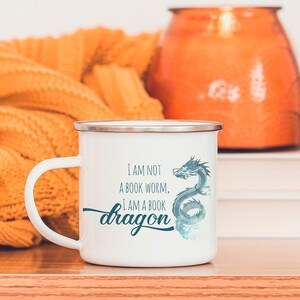 May include: White enamel mug with a blue dragon design and the text "I am not a book worm, I am a book dragon".