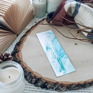 May include: A watercolor bookmark featuring a blue and silver sword with a white background.