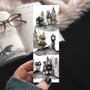 May include: A watercolor bookmark featuring three spooky houses with glowing windows. The houses are set against a dark, misty background with trees and a clock tower.