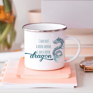 May include: White enamel mug with a blue watercolor dragon design and the text "I am not a book worm, I am a book dragon".