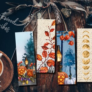 Könnte beinhalten: Vier Aquarell-Lesezeichen mit Herbstmotiven. Das erste Lesezeichen zeigt eine Waldszene mit einer Laterne und Kürbissen. Das zweite Lesezeichen zeigt einen Zweig mit roten und orangefarbenen Blättern. Das dritte Lesezeichen zeigt eine Waldszene mit einer Laterne und Kürbissen. Das vierte Lesezeichen zeigt ein Mondphasen-Design auf weißem Hintergrund.