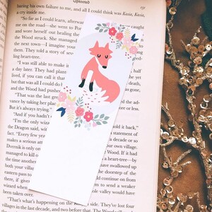 May include: A pink fox bookmark with floral designs. The bookmark is on top of a book with text about a story of a heart-tree.