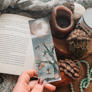 Peut inclure: Un marque-page aquarelle repr&eacute;sentant un arbre effrayant avec des lanternes lumineuses accroch&eacute;es &agrave; ses branches. La lune est pleine et le ciel est sombre. Ce marque-page est parfait pour ajouter une touche de fantaisie &agrave; votre exp&eacute;rience de lecture.