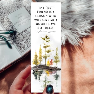 May include: A watercolor bookmark with a quote about friendship: "My best friend is a person who will give me a book I have not read." - Abraham Lincoln. The bookmark features a watercolor painting of a lake with trees reflected in the water.