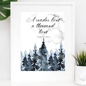 May include: A watercolor print with a quote by George R.R. Martin: "A reader lives a thousand lives." The quote is set against a background of a blue and gray watercolor forest.