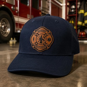 May include: A navy blue baseball cap with a mesh back and a tan leather patch on the front. The patch features a circular firefighter emblem with the text SEVERN FIREFIGHTER, a ladder, an axe, a hydrant, and a star of life symbol in the center.