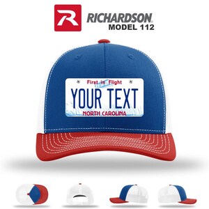May include: A Richardson Model 112 trucker hat with a blue crown, white mesh back, and red brim. The hat features a license plate design with the text "YOUR TEXT" and "NORTH CAROLINA". The top of the hat has a red button.
