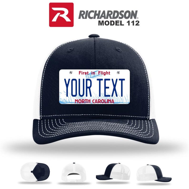 May include: Navy blue and white trucker hat with a license plate design. The hat features a navy blue crown and bill, a white mesh back, and a rectangular patch with the text "YOUR TEXT" and "NORTH CAROLINA". The hat also has the text "First in Flight".