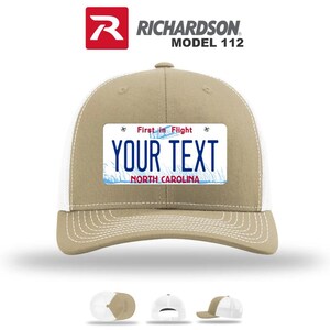 May include: A tan and white trucker hat with a license plate design. The license plate reads "YOUR TEXT" with "NORTH CAROLINA" below. The hat has a curved brim and a mesh back. The top of the hat has the text "RICHARDSON MODEL 112".