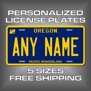 May include: A blue and yellow personalized license plate with the text "OREGON" and "PACIFIC WONDERLAND" in white. The plate has a space for a name, which is shown as "ANY NAME".