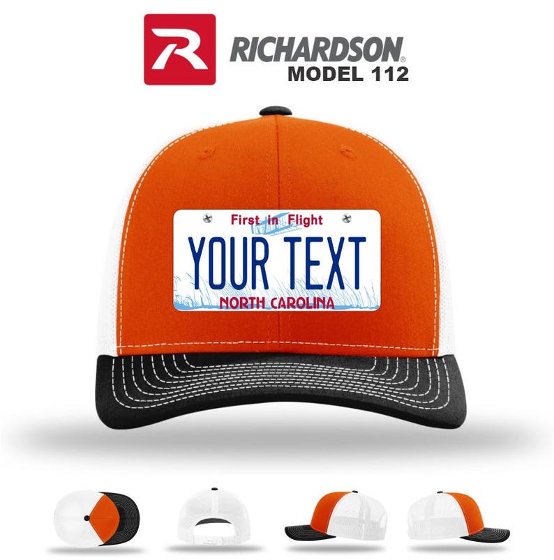 May include: Orange and white trucker hat with a black brim. The hat features a license plate design with the text "YOUR TEXT" and "NORTH CAROLINA". The hat is a Richardson Model 112.