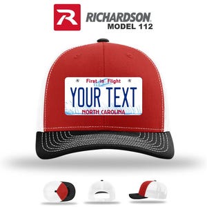 May include: A red, white, and black Richardson Model 112 trucker hat with a custom license plate design. The license plate reads "YOUR TEXT" with "First in Flight" above and "NORTH CAROLINA" below. The hat has a curved brim.