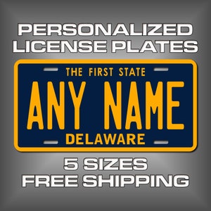 May include: A blue and yellow personalized license plate with the text "THE FIRST STATE" and "DELAWARE" and the words "ANY NAME" in large yellow letters. The text "5 SIZES FREE SHIPPING" is below the license plate.