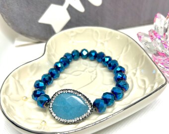 May include: A blue crystal beaded bracelet with a teardrop-shaped turquoise stone set in a silver bezel with clear rhinestones.