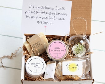 May include: A gift box filled with items for Mother's Day. The box contains a goat milk soap bar, a soy scented candle, a milk bath soak, a small glass terrarium with a plant, matches, and cookies. The box is decorated with brown paper and a handwritten note that reads "If I won the lottery, I would pick out the best nursing home ever for you no matter how far away it is from me."