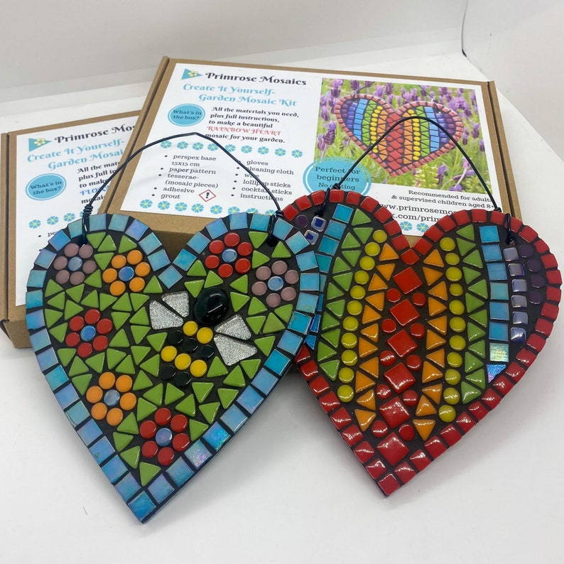 May include: Two heart-shaped mosaic craft kits with colorful glass tiles. The kits are ready to be assembled and feature a bee design and a rainbow pattern. The kits are part of a 'Create It Yourself Garden Mosaic Kit' set.